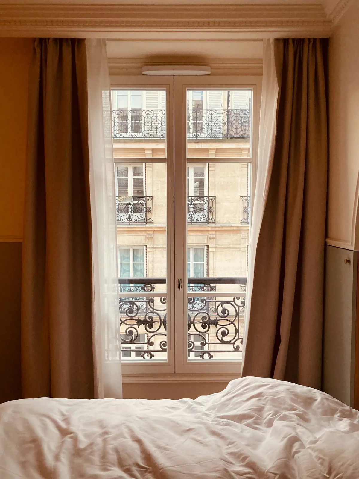 Chambre lumineuse avec grandes fenêtres et garde-corps en fer forgé — photographie d’illustration, inspiration Paris